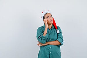 9 Things to Look Out for During Christmas Assignments 1 Female travel nurse thinking with hand on temple while on Christmas assignments